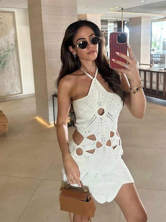 Woman taking a mirror selfie wearing a white crochet dress in an indoor setting.